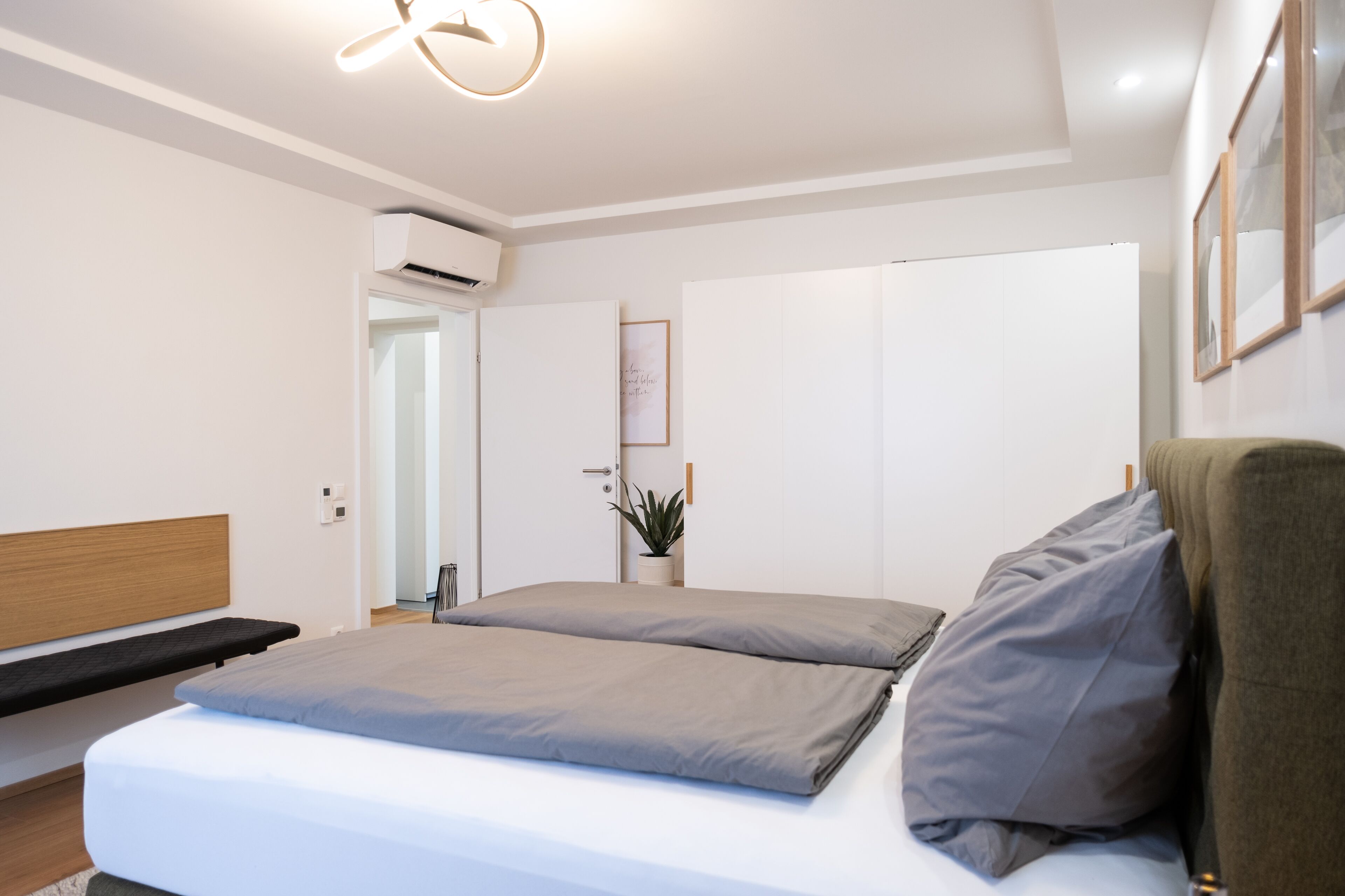 Une chambre à coucher moderne, équipée d’un lit, d’une table de chevet et d’un climatiseur fixé au mur.