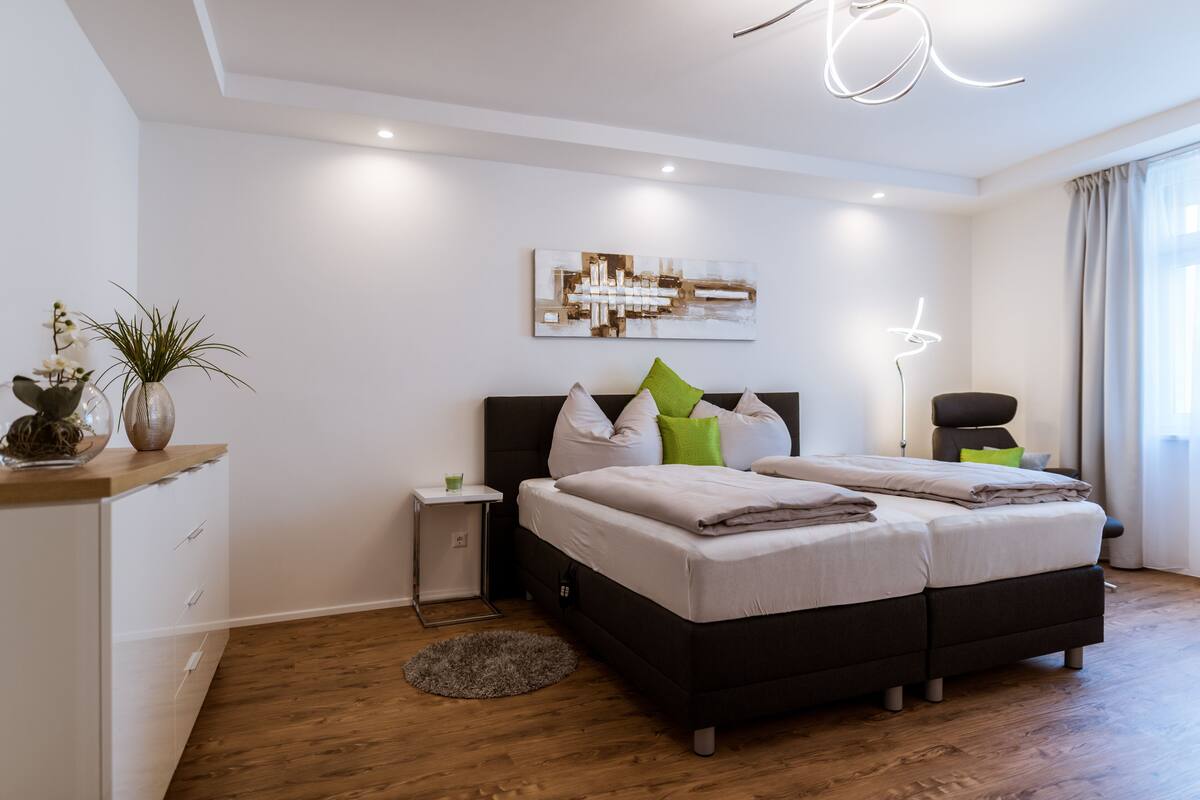 Un dormitorio moderno con una cama grande, una mesita de noche, una pequeña mesita auxiliar y una lámpara de pie.
