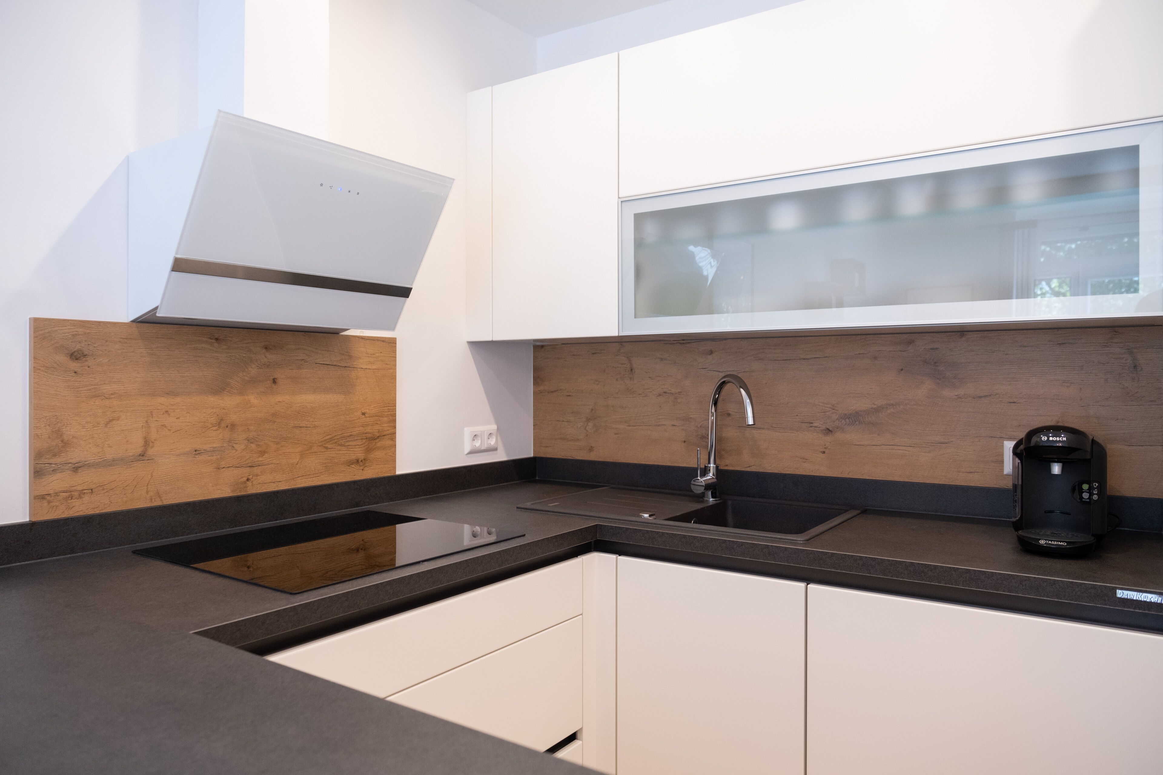 Una cocina moderna con horno empotrado, lavaplatos y cafetera.