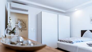Een moderne hotelkamer met een bed, een nachtkastje met een fruitschaal, een potplant en een wandairconditioner.