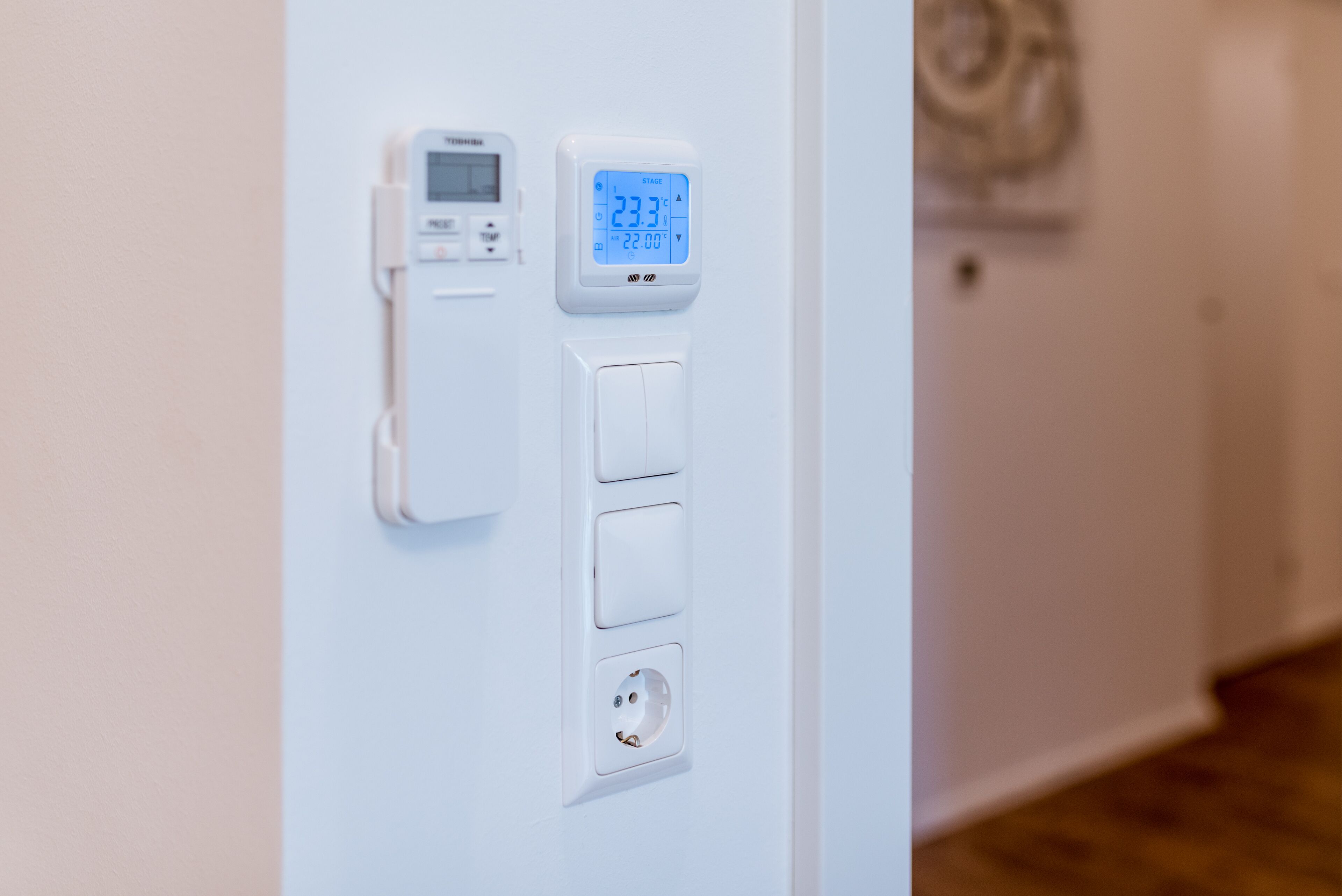 A wall-mounted thermostat with a digital display showing 23.3°C and 22:00.
