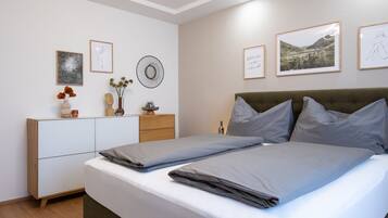 Ein ordentlich eingerichtetes Schlafzimmer mit Bett, Kommode und Wandbildern.