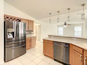 Kitchen features stainless steel appliances, light-colored cabinetry, and a large countertop.