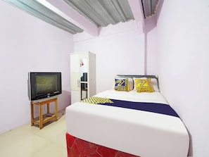 A small, single-bed room with a television on a wooden stand, a wardrobe, and a bed with patterned bedding. - Hotel O Biring Residence (Wargasaluyu)