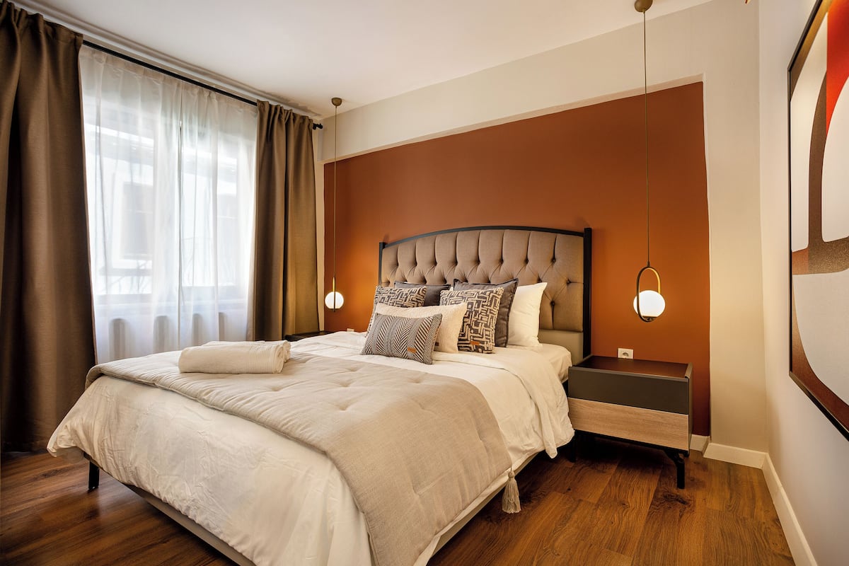 A neatly made bed with a headboard, a bedside table, and a wall-mounted light fixture.