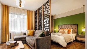 Een moderne hotelkamer met een hoekbank, een bed met een gestuifte hoofdeinde en een decoratieve scheidingswand.