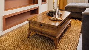 Een moderne woonkamer met een flatscreen televisie aan de muur, een houten salontafel en een bank.