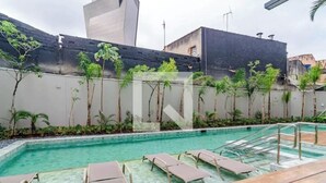 Una piscina con lettini e un edificio moderno sullo sfondo.