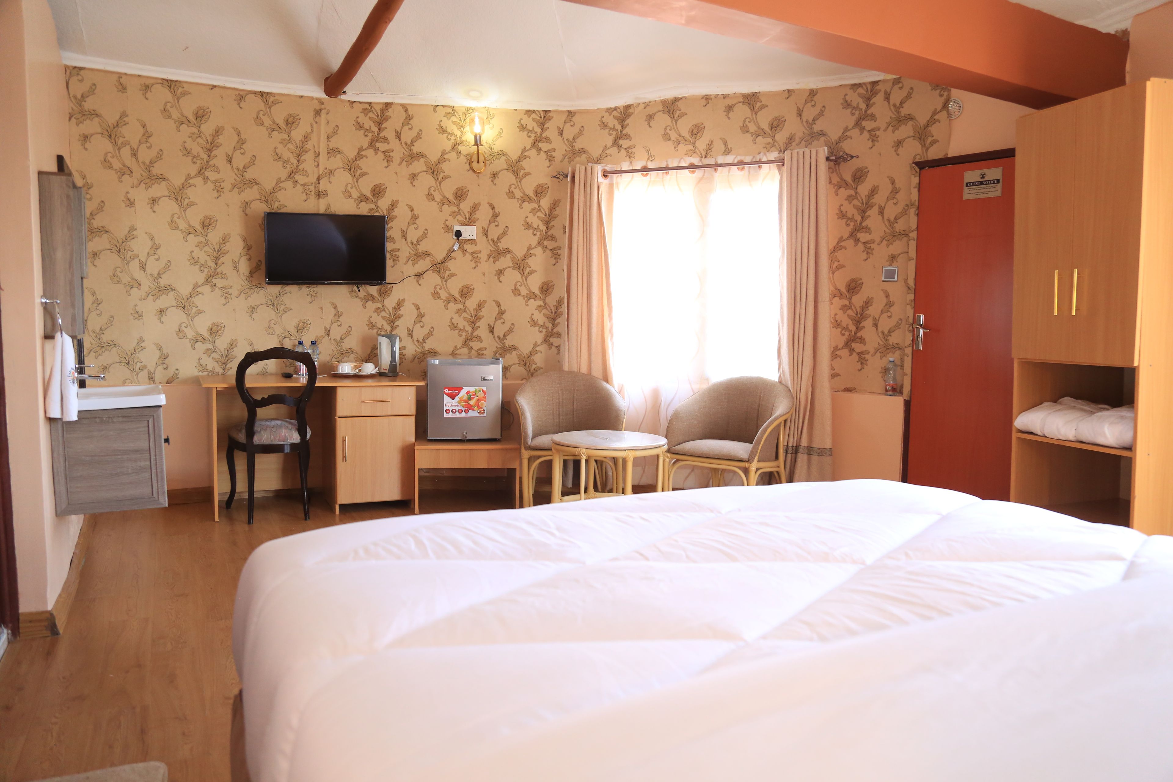A hotel room with a bed, a desk with a chair, a television, and a wardrobe.