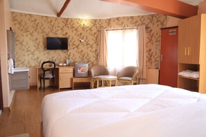 Hotellihuone, jossa on sänky, työpöytä tuolilla, televisio ja vaatekaappi.