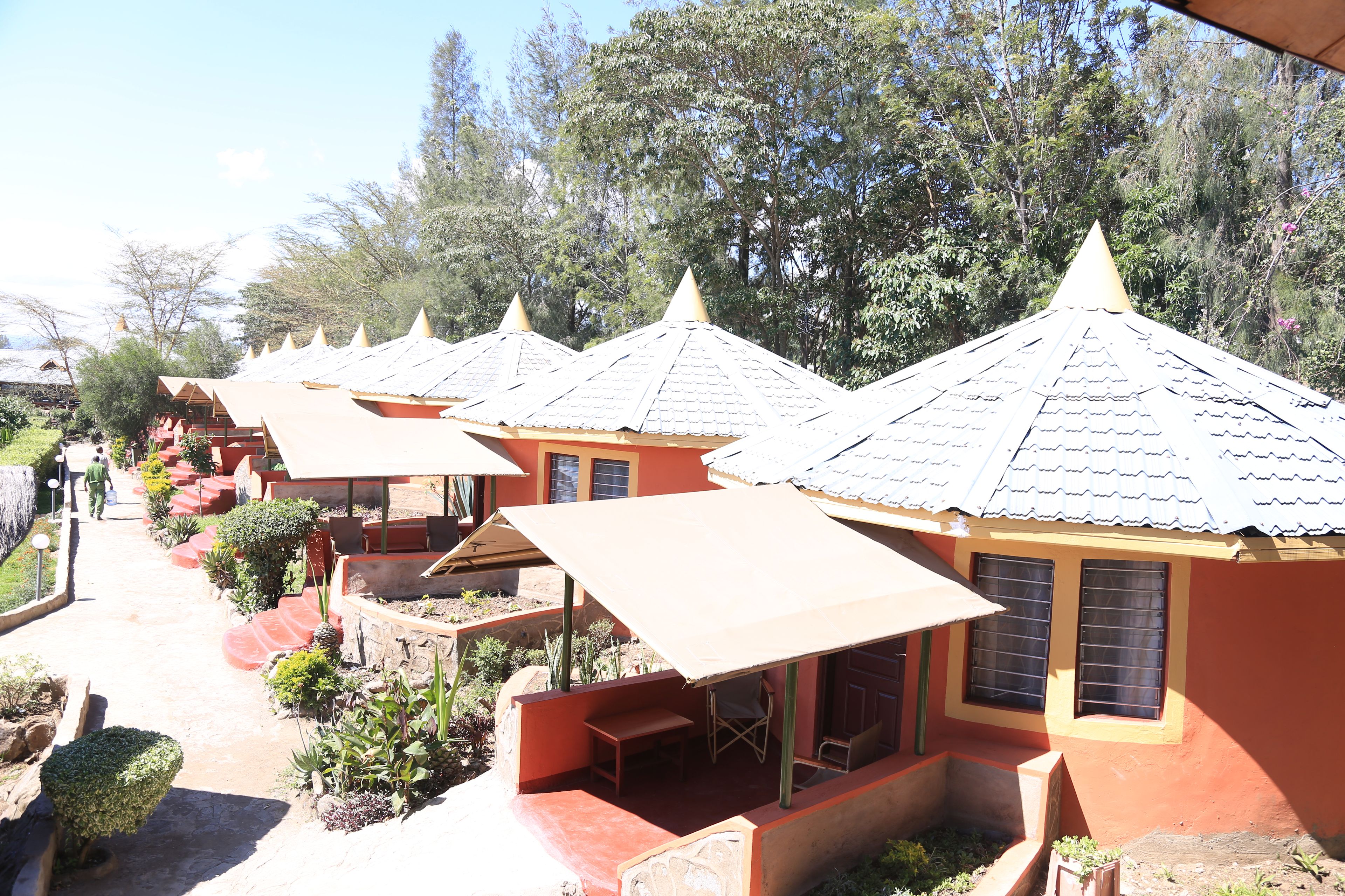 A row of small, single-story buildings with conical roofs, each with a small porch and a table and chair.