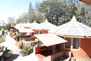 A row of small, single-story buildings with conical roofs, each with a small porch and a table and chair.