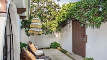 A cozy outdoor seating area with wicker chairs and a decorative umbrella.