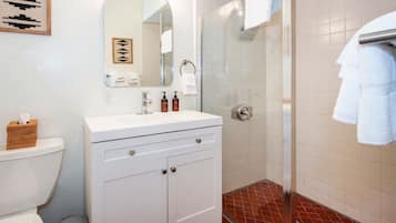 A bathroom with a white vanity, a glass shower enclosure, and a tiled floor.
