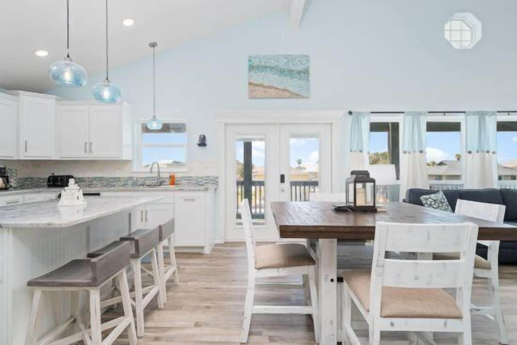 A kitchen with white cabinets, a wooden island with bar stools, and pendant lights.