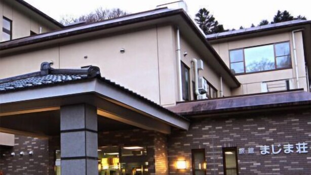 Un edificio con entrada cubierta, fachada de ladrillo y un letrero con caracteres japoneses.