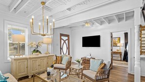 Ein geräumiges Wohnzimmer mit hoher Decke, einer großen Kronleuchter, einem Fernseher und Blick auf die Stadt durch ein Fenster.