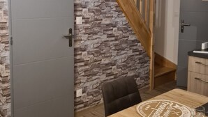 Un comedor con una mesa y sillas de madera, una pared de piedra y una escalera de madera.