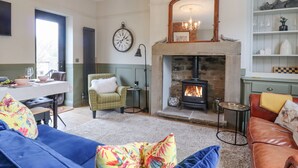 A cozy living room with a fireplace, a dining area with a table set for two, and a comfortable seating area with sofas and cushions. - No 47, Haworth (Keighley)