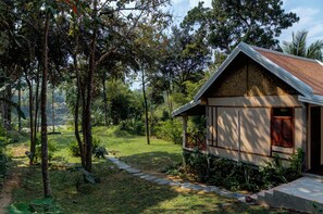 Une maison avec un toit en pente, entourée d’un jardin où un sentier de pierres mène à l’entrée.