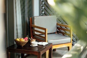A wooden chair with a cushion, a small table with a basket of fruit, a bowl, and a plate. - My Dream Boutique Resort (Luang Prabang)