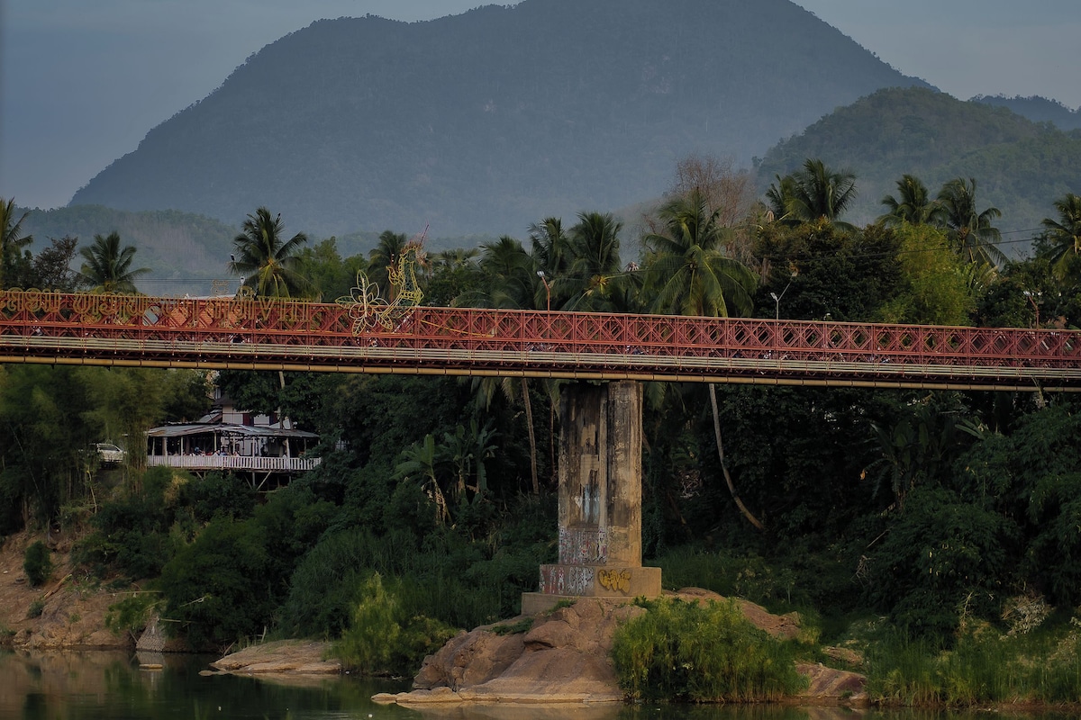 A bridge over a river with a mountain in the background.