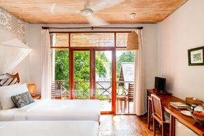 Ein Zimmer mit einem Bett, einem Schreibtisch, einem Fernseher und einem Balkon mit Blick auf Grünflächen.