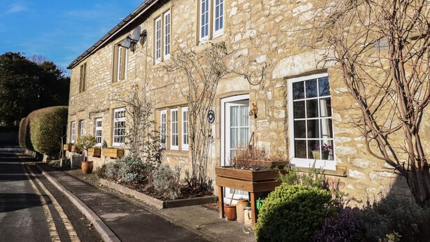 A stone building with multiple windows and a small garden area with potted plants.