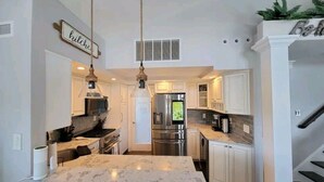 A modern kitchen with white cabinetry, a marble island, and stainless steel appliances. - HOT TUB & Bicycles - Walking distance to the BEACH, bay, restaurants, & shopping (Brigantine)