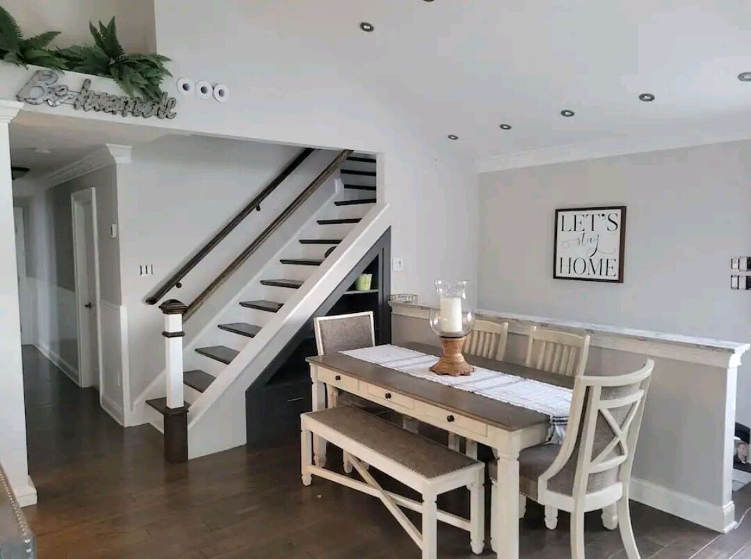 Ein Essbereich mit einem Holztisch und Stühlen, einer Bank und einer Treppe, die in einen anderen Raum führt.