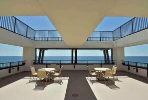 A rooftop terrace with a clear view of the ocean, furnished with tables and chairs, and a central open space. - Dream by the Sea 806-Gulf Views-Sleeps 3 (Panama City Beach)