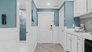 Un pasillo estrecho con armarios blancos y una puerta que da a una habitación.