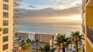 A hotel with multiple floors, a pool, and a view of the ocean.
