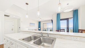 A modern kitchen with a double sink, marble countertops, and pendant lighting.