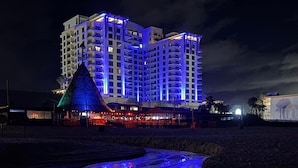 A multi-story hotel with a modern design, featuring balconies and a rooftop terrace.