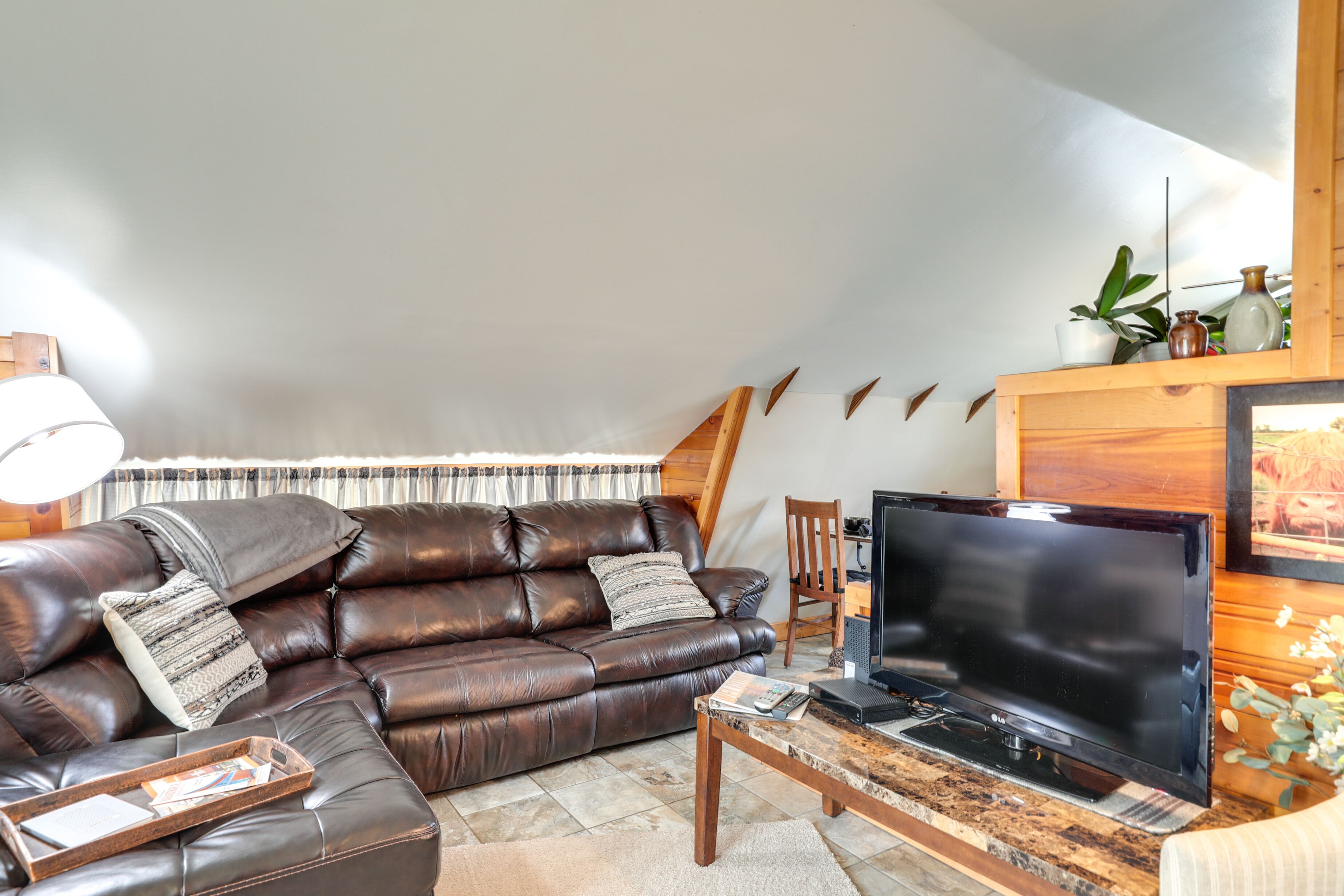 Una sala de estar moderna con un sofá de cuero, un televisor de pantalla plana y una mesa de centro de madera.