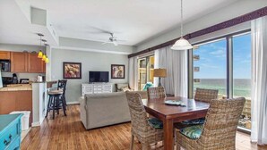 A spacious living area with a dining table, wicker chairs, a sofa, and a view of the ocean. - Vacation Station 716-Ocean View-Sleeps 4 (Panama City Beach)
