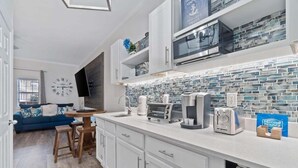Una cocina moderna con armarios blancos, salpicadero de azulejos y un microondas empotrado.