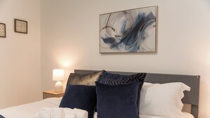 A neatly made bed with white and navy pillows, a blue throw blanket, and a wall-mounted abstract painting. - 2 BD/1 BA Home- Wine Country Getaway (Santa Rosa)