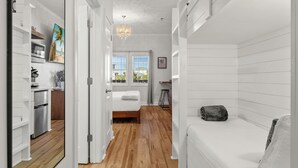 Un dormitorio moderno con suelo de madera, una cama, una mesita de noche y una ventana con vistas al exterior.