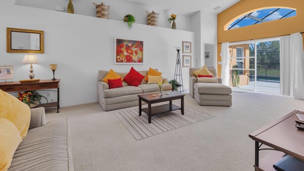 Een ruime woonkamer met een bank, fauteuils en een salontafel. Er is een groot raam met uitzicht op het omliggende landschap.