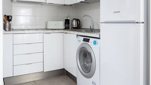A modern kitchen with white cabinets, a built-in washing machine, a microwave, and a coffee maker. - Home2Book Disco Duplex in Las Américas Beach (Arona)