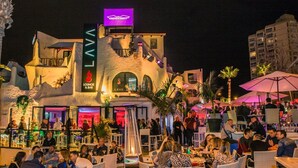 A lively outdoor bar area with a lava-themed facade, outdoor seating, and a crowd of people. - Home2Book Disco Duplex in Las Américas Beach (Arona)