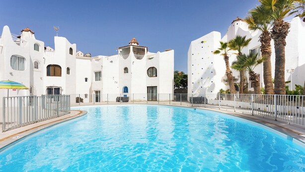 A swimming pool with white buildings in the background. - Home2Book Disco Duplex in Las Américas Beach (Arona)