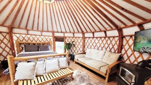 L’intérieur d’une yourte, avec un lit, un canapé et une cheminée.