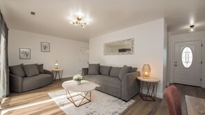 A modern living room with two grey sofas, a white coffee table, and a small side table with a lamp.
