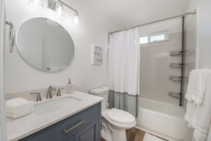 A modern bathroom with a round mirror, a sink, a toilet, and a shower area. - Amazing Santa Rosa Wine Escape Home (Santa Rosa)