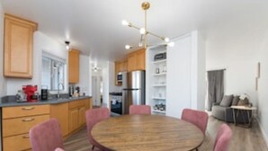 A modern kitchen with wooden cabinets, a round dining table with chairs, and a pendant light.