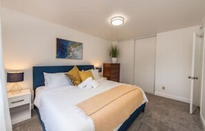 A bedroom with a bed, nightstand, bedside lamp, wall art, and a door. - Amazing Santa Rosa Wine Escape Home (Santa Rosa)