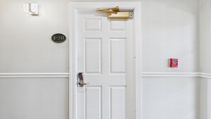 Una puerta blanca con cerradura electrónica, un buzón y un detector de incendios en la pared.